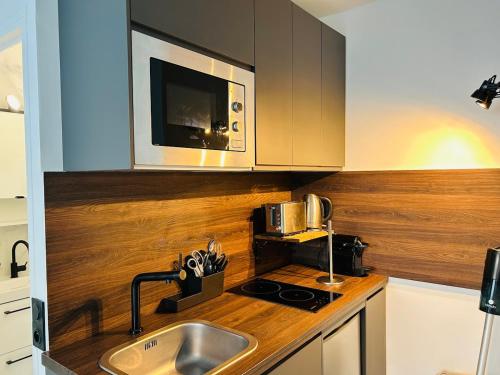 une cuisine avec un évier et un micro-ondes dans l'établissement Le Joli Petit Morny Hypercentre, à Deauville
