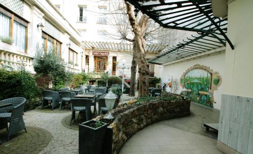 a patio with tables and chairs and a tree at Hôtel Crystal Reims Centre in Reims