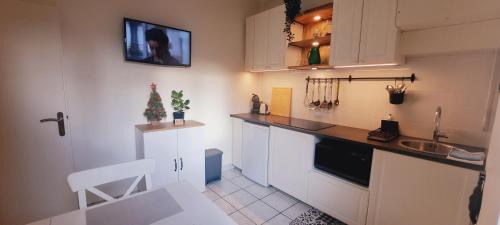 une cuisine avec des placards blancs et un arbre de Noël sur le mur dans l'établissement Appartement 3 étoiles au cœur d'Uriage les bains, à Vaulnaveys-le-Haut