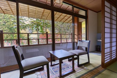 a room with two chairs and a table on a balcony at Ryokan Koyokan in Yasugi