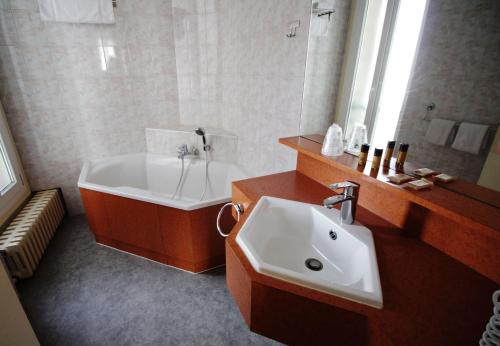 a bathroom with a tub and a sink and a bath tub at Hôtel Crystal Reims Centre in Reims