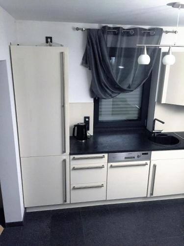 a kitchen with a white refrigerator and a sink at Moderne 3 Zimmer Wohnung mit separatem Eingang in Hannover