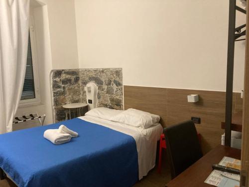 a bedroom with a blue bed with towels on it at Bella Napoli Guesthouse Trattoria Pizzeria in La Spezia