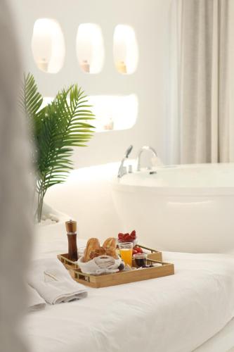 バトゥルーンにあるAqualand Hotel & Resortの浴室のベッドの上に置かれた食べ物のトレイ