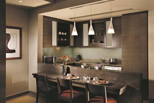 a kitchen with a bar with chairs and a table at Park Arjaan by Rotana, Abu Dhabi in Abu Dhabi