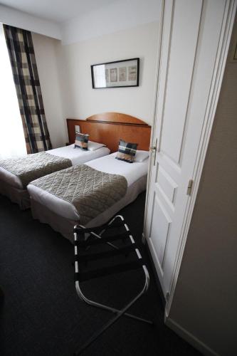 a hotel room with two beds and a door at Hôtel Crystal Reims Centre in Reims