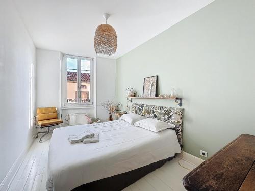 une chambre blanche avec un grand lit et une chaise dans l'établissement Le Cocon d'Ange Au Centre 4pers Wifi, à Clermont-Ferrand