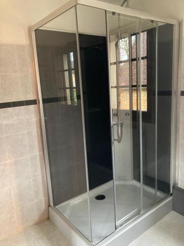 La salle de bains est pourvue d'une douche avec des portes en verre. dans l'établissement Maison la Douime, à Azerat