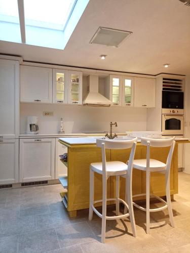 a kitchen with white cabinets and a sink and stools at Waterfront Historical Villa Perast in Perast