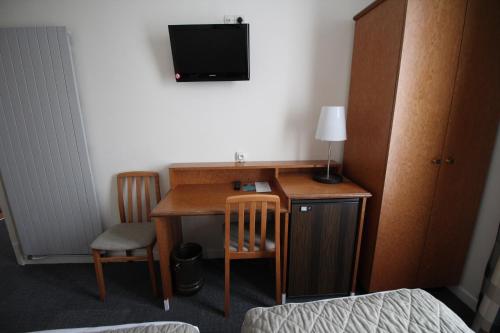 a room with a desk and a tv on a wall at Hôtel Crystal Reims Centre in Reims