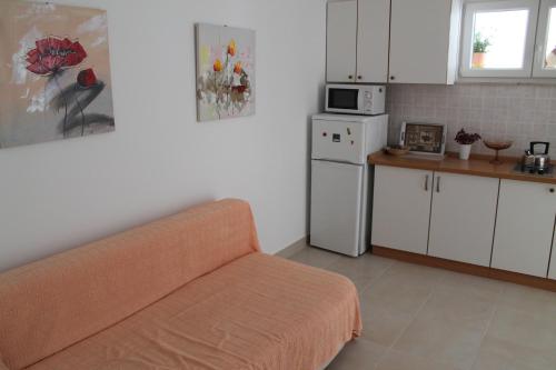 a kitchen with a couch and a white refrigerator at Adria Apartments in Podgora