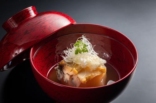 a red bowl of soup with food in it at Ichiboukan Hanare Kai in Kyotango