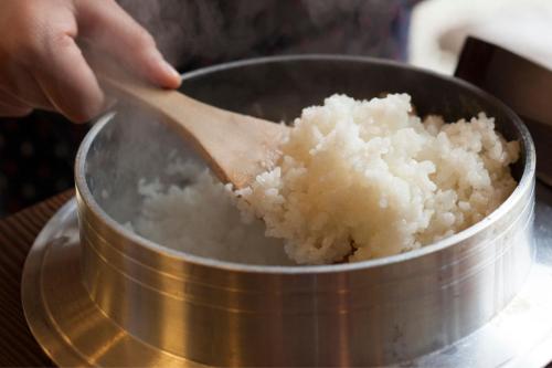 a person holding a wooden spoon in a pot of rice at Ichiboukan Hanare Kai in Kyotango