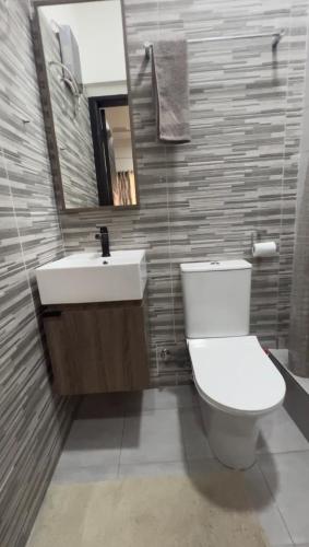 a bathroom with a toilet and a sink and a mirror at Pebbles Nest in Kwabenya