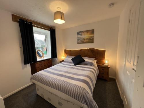 a bedroom with a bed and a window at Malt-Barn Conversion, with access to Pool & Hot Tub-at Fox Valley Cottages in Lansallos