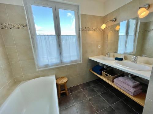 une salle de bain avec une baignoire, un lavabo et une fenêtre dans l'établissement Kerlud, maison avec garden, à Locmariaquer