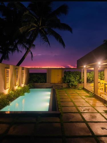 a villa with a swimming pool at night at Villa Sea Queen in Ambalangoda