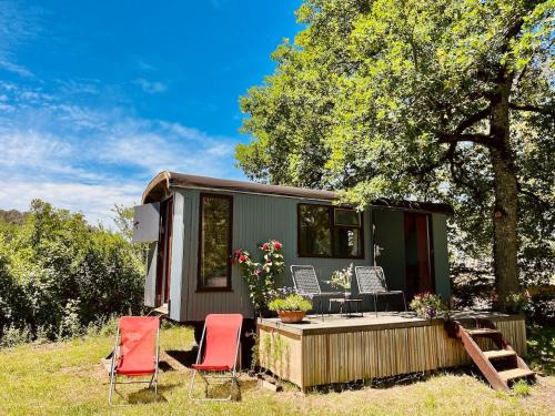 une petite maison verte avec deux chaises et une terrasse dans l'établissement Wooden Cabin - Outdoor Kitchen - Superb Location!, à Capdrot