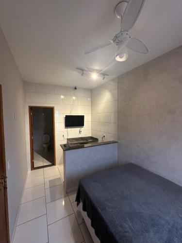 1 dormitorio con 1 cama y cocina con ventilador de techo. en Arraial Hospedagem, en Arraial do Cabo