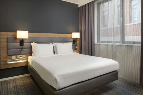 a large bed in a hotel room with two lamps at Moxy Glasgow Merchant City in Glasgow