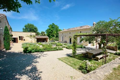 a garden with a building and a bench in a yard at Domaine de Pertignas in Saint-Vincent-de-Pertignas