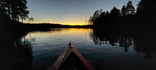 a person in a canoe on a lake at sunset at The hunters-lodge in Ludvika
