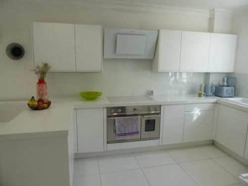 a white kitchen with white cabinets and a stove at Modern townhouse in Mountwise in Plymouth