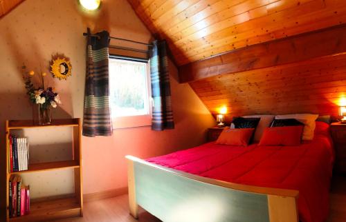 - une chambre avec un lit rouge et un plafond en bois dans l'établissement Gîtes de Stouet, à Artalens-Souin