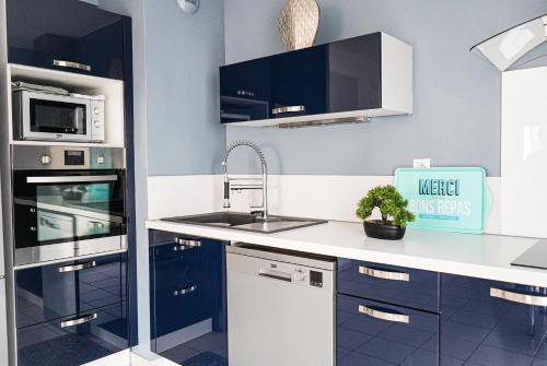 une cuisine avec un évier et un micro-ondes dans l'établissement Bel appartement climatisé & parking, à Perpignan