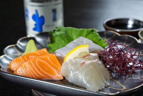 a plate of sushi and vegetables on a table at 城下町に佇む癒しの宿 旅館 大政 in Karatsu