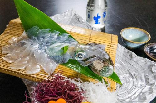 a plastic fish on a bamboo cutting board with vegetables at 城下町に佇む癒しの宿 旅館 大政 in Karatsu