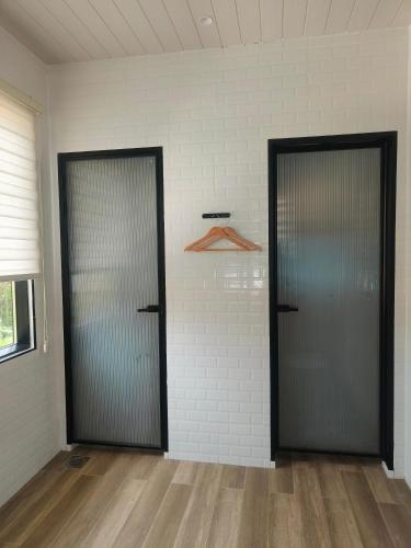 two doors in a room with wood floors and white walls at The Pampines Villa, Mount Kinabalu in Ranau