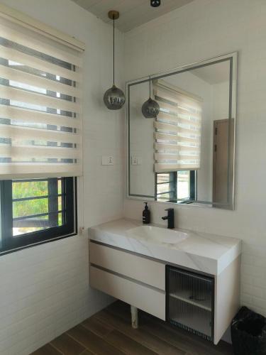 a white bathroom with a sink and a mirror at The Pampines Villa, Mount Kinabalu in Ranau