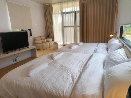 a hotel room with two beds and a flat screen tv at The Pampines Villa, Mount Kinabalu in Ranau