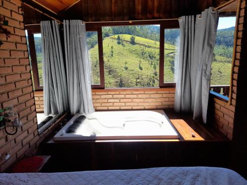eine Badewanne in einem Raum mit Fenster in der Unterkunft Paraíso da serra visconde de Mauá in Visconde De Maua