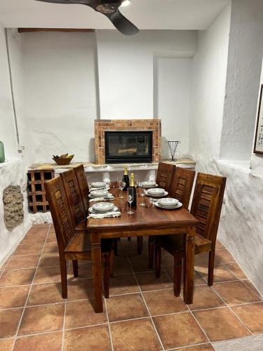 a dining room table with chairs and a fireplace at Rustic house with swimming pool in Las Pesas
