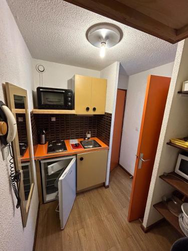 une petite cuisine avec une cuisinière et un micro-ondes dans l'établissement Studio 4 personnes les Orres vue sur le lac, aux Orres