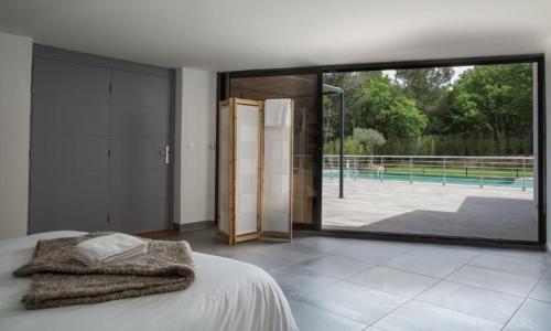 une chambre avec un lit et une grande fenêtre en verre dans l'établissement Près d'Avignon villa de rêve piscine, à Saint-Geniès-de-Comolas