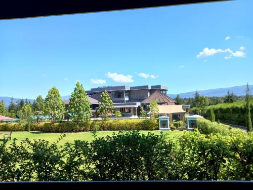 a view of a building with a lawn and trees at Olempiaus Gardens Hotel in Mai Mahoro