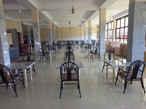 a dining room with tables and chairs and a lobby at Olempiaus Gardens Hotel in Mai Mahoro