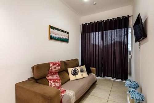 ein Wohnzimmer mit einer Couch und einem Fenster in der Unterkunft Casa de condomínio HP2 - Ideal para turistas e empresas - 7 min de carro das praias Tupi e Ocian in Praia Grande