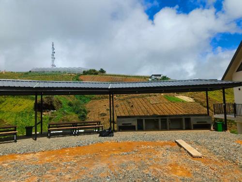 a building with two benches and a roof at The Pampines Villa, Mount Kinabalu in Ranau