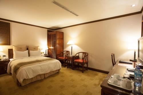 a bedroom with a bed and a desk and a chair at Rich Garden Hotel in Taipei