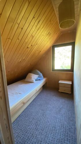 a bed in a wooden room with a window at Jaśminowy ogród in Brenna