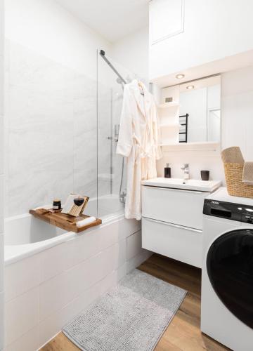 une salle de bain blanche avec une baignoire et un lavabo dans l'établissement Au Pas de Bouffay, perched nest, medieval quarter, à Nantes
