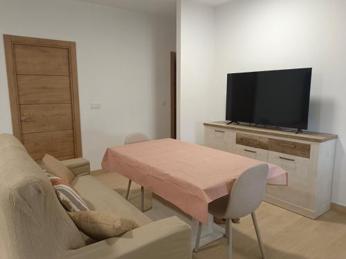a living room with a table and a flat screen tv at Apartamentos La Fuente in Almodóvar del Río