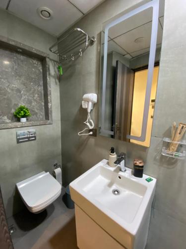a bathroom with a sink and a toilet and a mirror at Luxury Vello Stay Supernova in New Delhi
