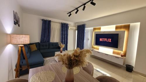 un salon avec un canapé bleu et une télévision dans l'établissement Rehab Elegant Apartment - New Cairo, à Burg el-Ḥudûd