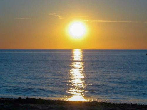 un coucher de soleil sur l'océan avec le soleil dans le ciel dans l'établissement Künstlerhaus, à Ribnitz-Damgarten