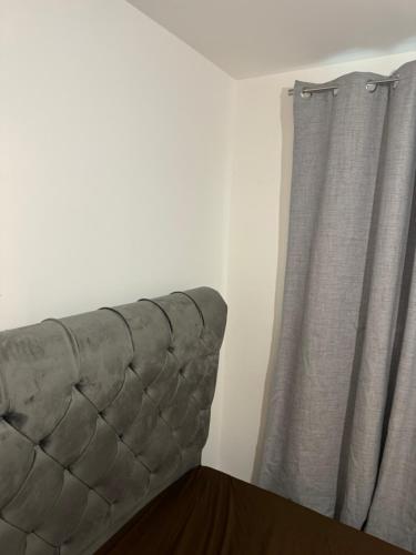 a couch sitting next to a window with a curtain at one bedroom-modern-luxury-private-free wifi-gravesend in Gravesend